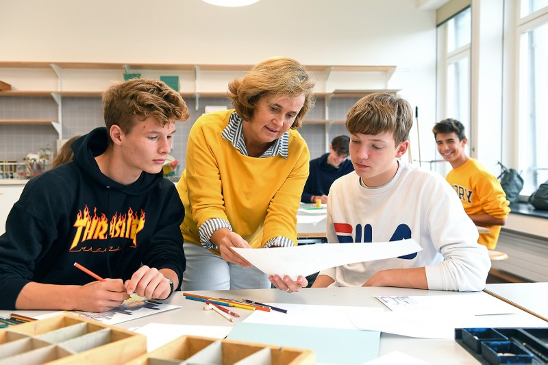 Bildnerisches Gestalten am Gymnasium: Eine Lehrperson unterstützt zwei Schüler.